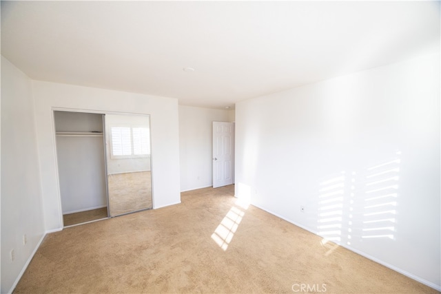 unfurnished bedroom featuring light carpet and a closet