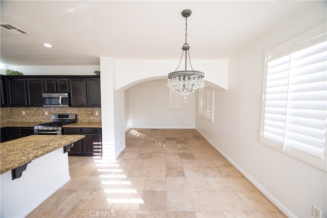 kitchen featuring appliances with stainless steel finishes, tasteful backsplash, a wealth of natural light, light tile patterned floors, and a chandelier