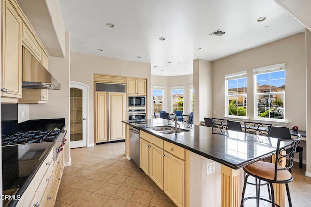 kitchen with sink, built in appliances, an island with sink, a kitchen bar, and light tile patterned floors