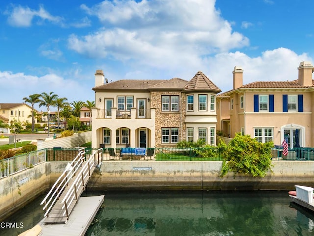 rear view of property featuring a balcony and a water view