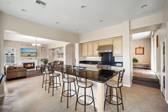 kitchen featuring sink, a kitchen breakfast bar, light hardwood / wood-style floors, extractor fan, and cream cabinetry