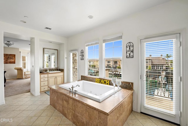 bathroom with tile patterned floors, vanity, and tiled bath