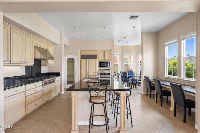 kitchen with a center island with sink, sink, built in appliances, range hood, and light tile patterned flooring