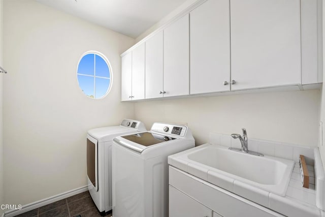 laundry room with cabinets, sink, washer and dryer, and dark tile patterned flooring