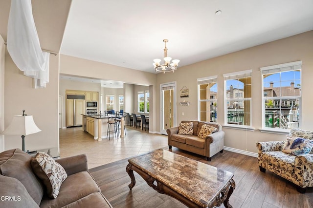 living room featuring plenty of natural light, a notable chandelier, and light hardwood / wood-style flooring