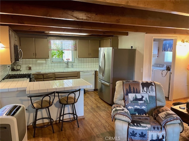 kitchen with dark wood-type flooring, tile counters, backsplash, and stainless steel appliances