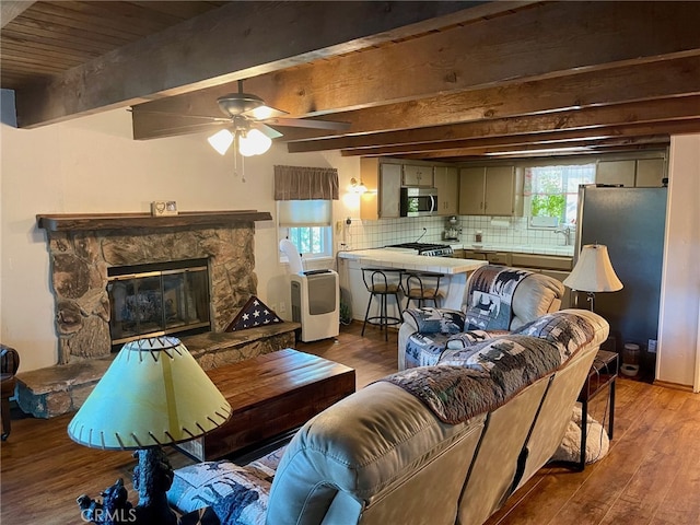 living room featuring beam ceiling, a fireplace, hardwood / wood-style flooring, and ceiling fan