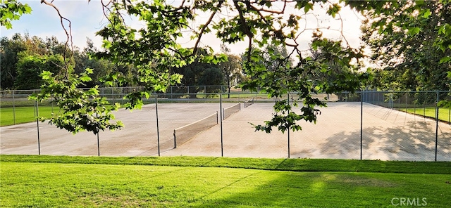 view of tennis court featuring a lawn