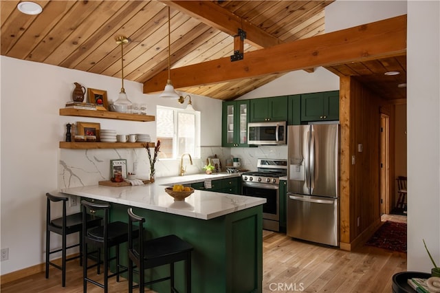 kitchen with kitchen peninsula, green cabinetry, a breakfast bar area, stainless steel appliances, and light wood-type flooring