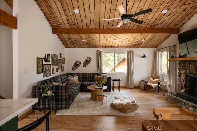 living room featuring a stone fireplace, light hardwood / wood-style flooring, lofted ceiling with beams, and plenty of natural light