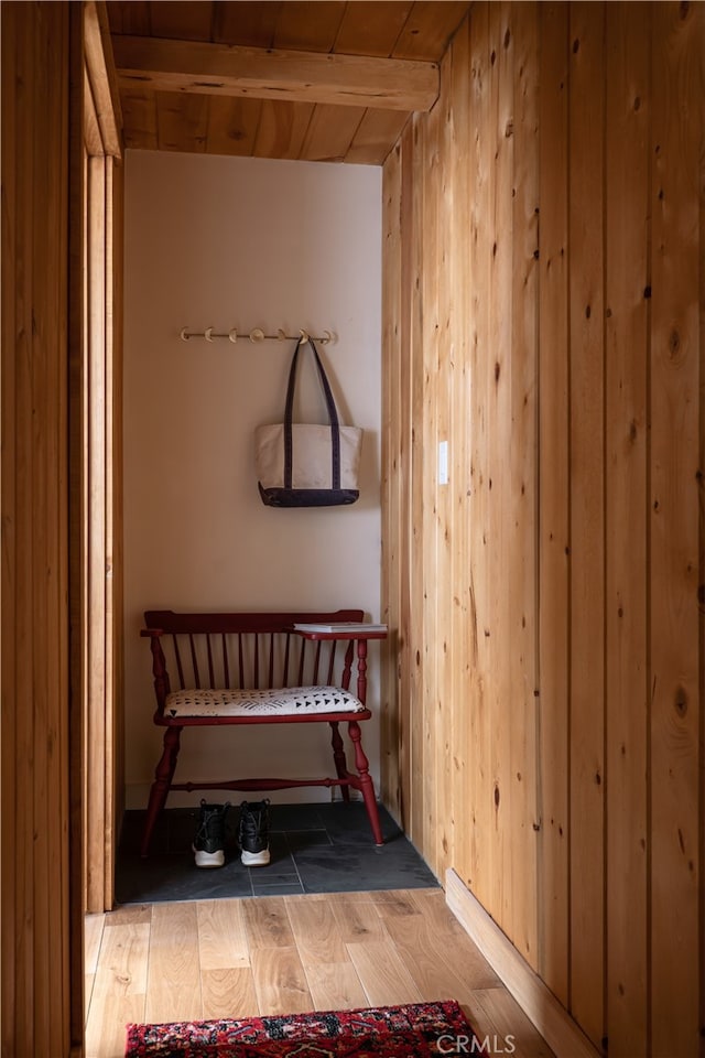 interior space with light wood-type flooring, wooden ceiling, and wooden walls