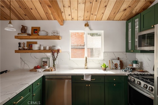 kitchen with appliances with stainless steel finishes, light stone counters, backsplash, sink, and green cabinets