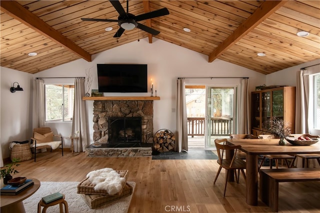 dining room with wood-type flooring, beam ceiling, ceiling fan, and a fireplace