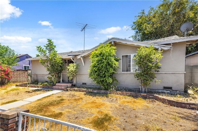 view of front facade with crawl space, fence, and stucco siding