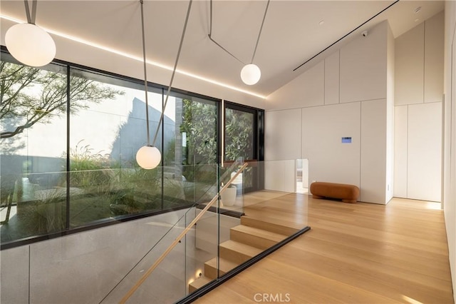 staircase featuring vaulted ceiling, plenty of natural light, and wood-type flooring