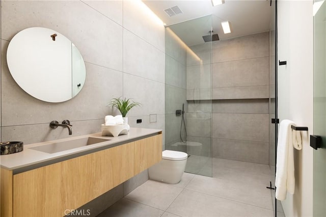 bathroom with a shower with shower door, vanity, and tile walls