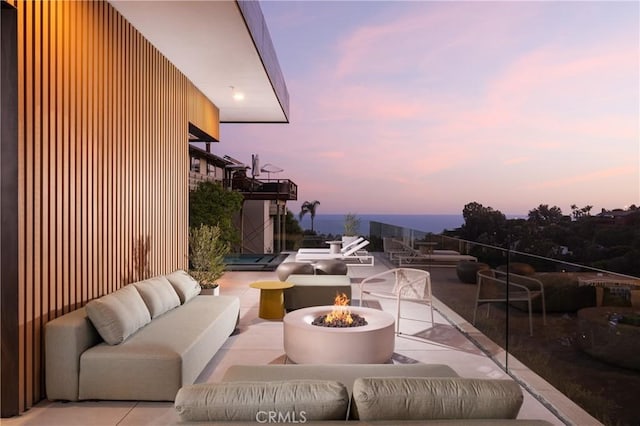 patio terrace at dusk featuring an outdoor living space with a fire pit