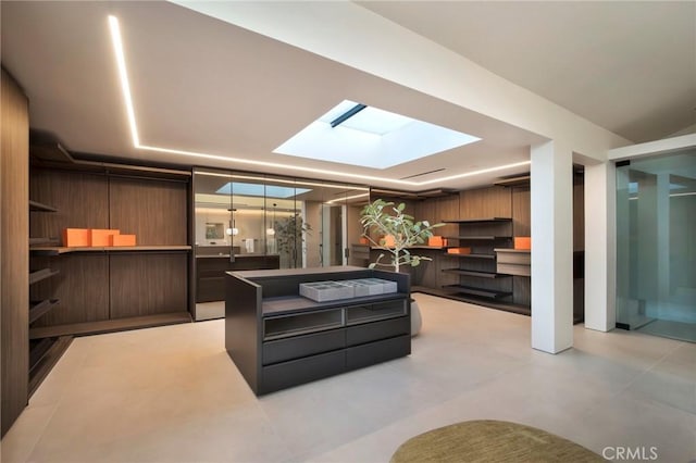 kitchen with a skylight, dark brown cabinets, wood walls, and a kitchen island