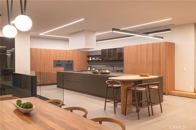 kitchen featuring kitchen peninsula, pendant lighting, a breakfast bar area, wooden walls, and custom exhaust hood