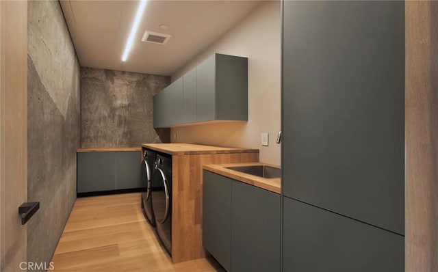 washroom featuring washer and clothes dryer, light wood-type flooring, sink, and cabinets