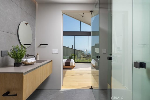 bathroom featuring a shower with shower door and vanity