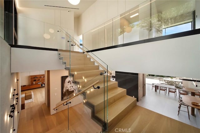 stairs featuring track lighting, a towering ceiling, and hardwood / wood-style flooring