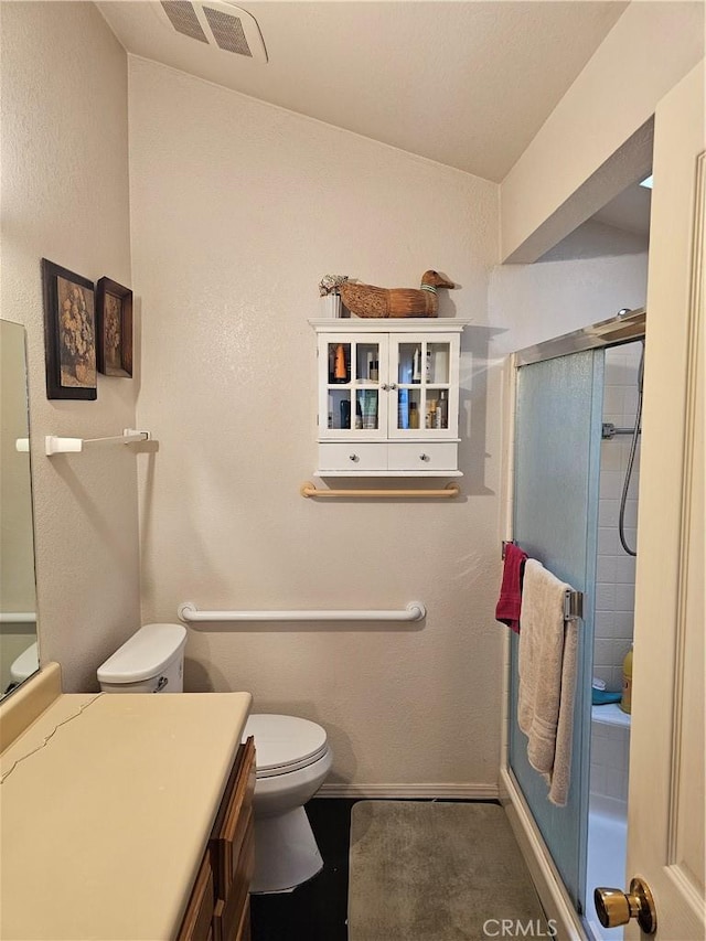 bathroom featuring vanity, toilet, and a shower with shower door