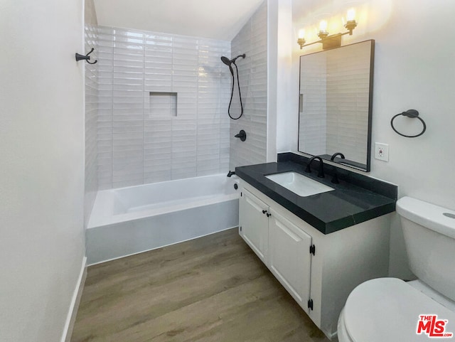 full bathroom featuring hardwood / wood-style flooring, vanity, toilet, and tiled shower / bath