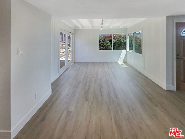 interior space with beam ceiling, a healthy amount of sunlight, and light hardwood / wood-style flooring