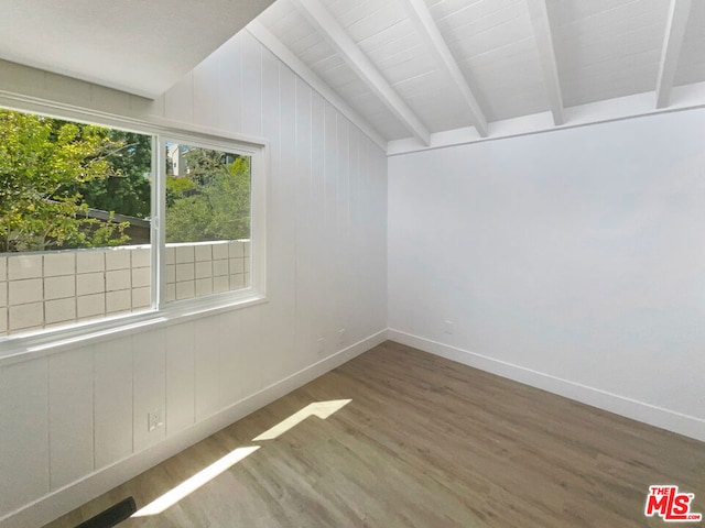 unfurnished room featuring vaulted ceiling with beams, hardwood / wood-style flooring, and wooden walls