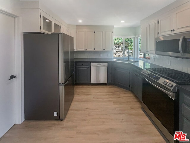 kitchen featuring appliances with stainless steel finishes, backsplash, sink, white cabinets, and light hardwood / wood-style floors