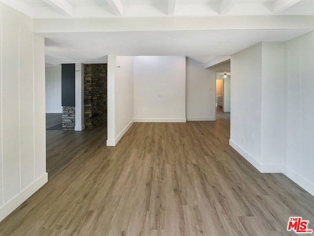 unfurnished room featuring beamed ceiling, wood-type flooring, and a fireplace