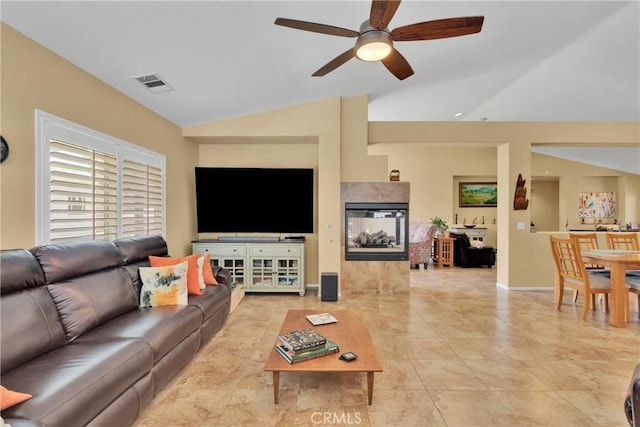 living room with a tile fireplace, ceiling fan, lofted ceiling, and light tile patterned flooring