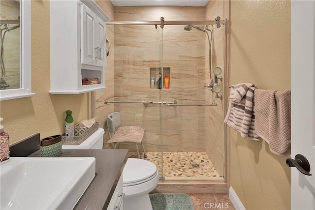 bathroom with tile patterned floors, vanity, toilet, and walk in shower