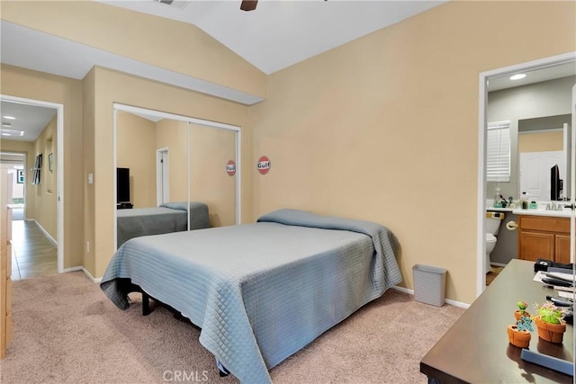 bedroom with light carpet, ensuite bath, vaulted ceiling, ceiling fan, and a closet