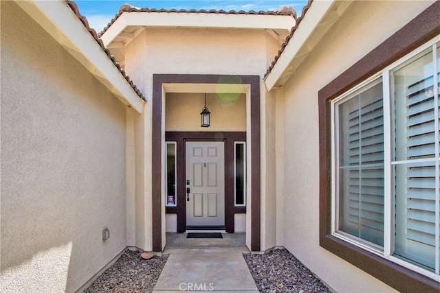 property entrance featuring stucco siding and a tiled roof