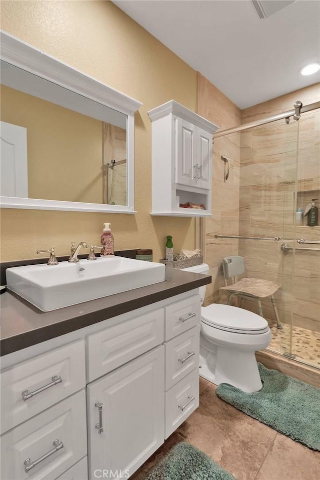 bathroom featuring toilet, a stall shower, and vanity