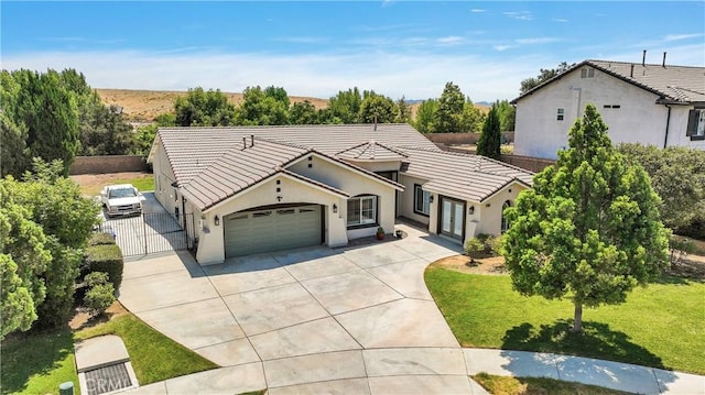 view of front of property with a tile roof, concrete driveway, fence, and a front yard