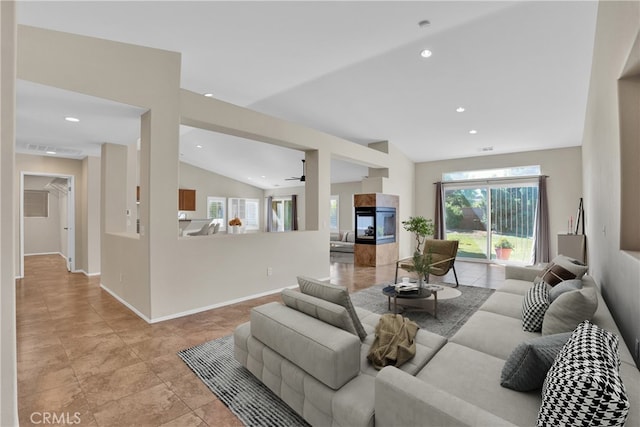 living room with a tiled fireplace, ceiling fan, and lofted ceiling