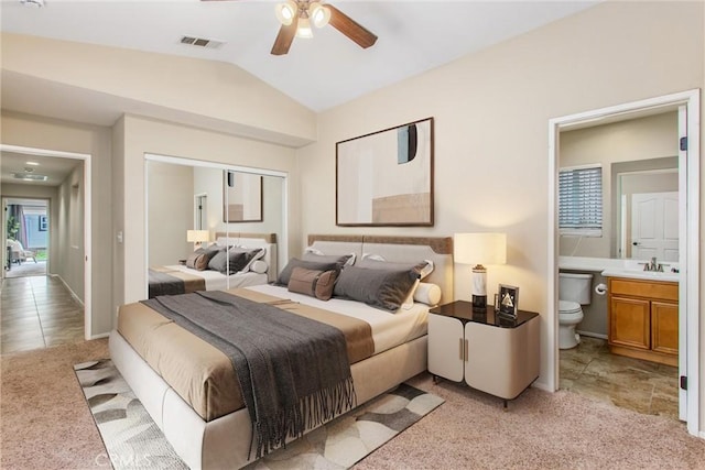 bedroom with ensuite bath, vaulted ceiling, light colored carpet, and visible vents