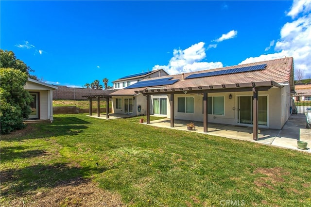 back of property featuring roof mounted solar panels, stucco siding, a yard, a pergola, and a patio