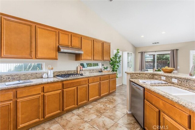 kitchen with under cabinet range hood, appliances with stainless steel finishes, brown cabinetry, and a sink