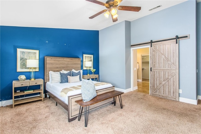 bedroom with visible vents, a barn door, carpet, and baseboards