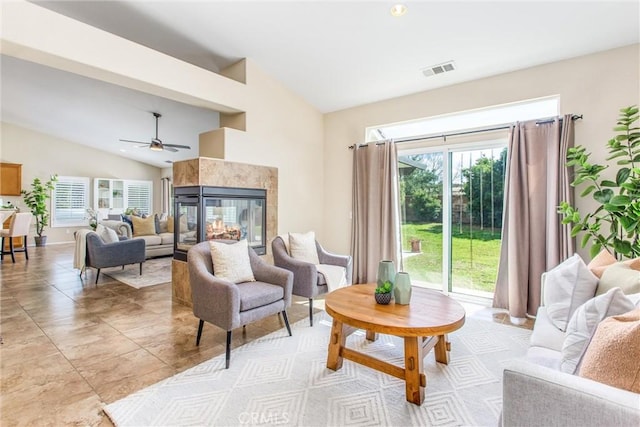living room featuring visible vents, lofted ceiling, a ceiling fan, and a tiled fireplace
