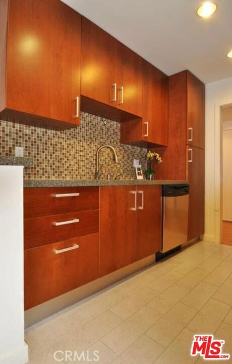 kitchen featuring light tile patterned flooring, backsplash, stone countertops, and stainless steel dishwasher