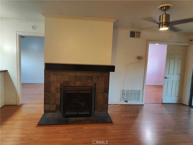 unfurnished living room with a tile fireplace, ceiling fan, hardwood / wood-style floors, and crown molding