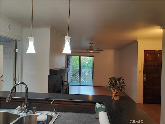 kitchen with sink, hardwood / wood-style flooring, decorative light fixtures, a multi sided fireplace, and ornamental molding