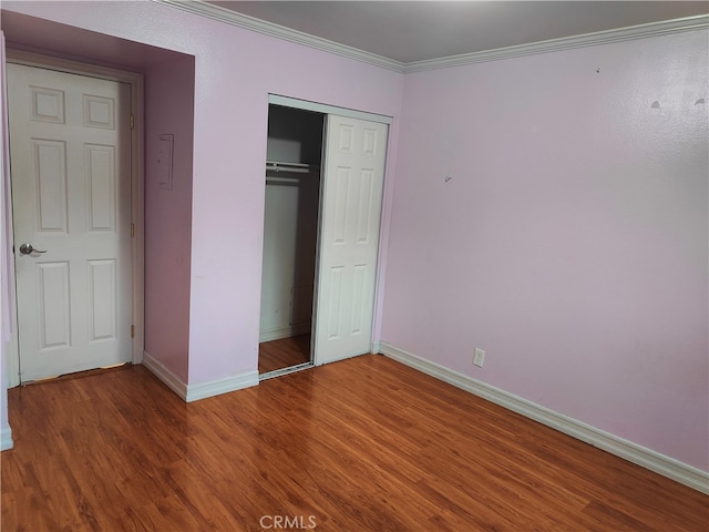 unfurnished bedroom featuring a closet, wood-type flooring, and ornamental molding