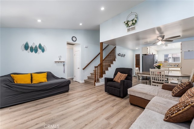 living room featuring vaulted ceiling, light wood-type flooring, and ceiling fan