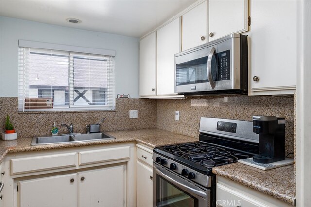 kitchen with backsplash, sink, appliances with stainless steel finishes, and white cabinetry